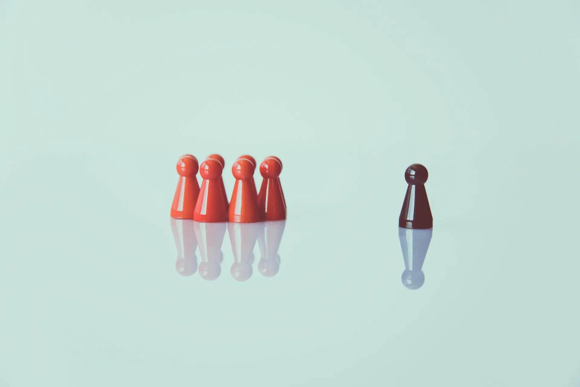 Acht rode pionnen en een zwarte pion staat apart van de groep.